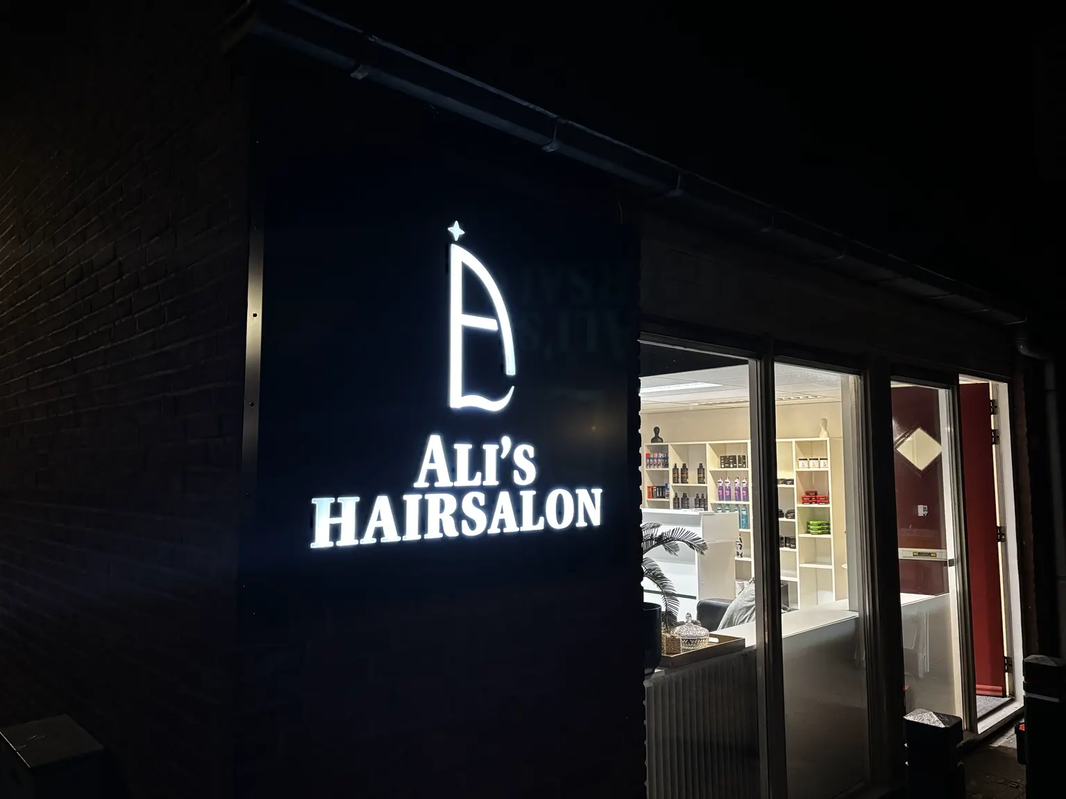 Verlichte gevelreclame van Ali’s Hairsalon